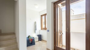 A hallway with a staircase leading to a room, a window with blinds, and a door to an outdoor area. - Poseidon Residence (San Vito Lo Capo)