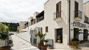 A street with white buildings, a gate, and potted plants. - Poseidon Residence (San Vito Lo Capo)
