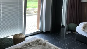 A modern hotel room with a large bed, a view of the outdoors, and a sliding door leading to a balcony. - Jagdschloss Windenhütte (Thale)