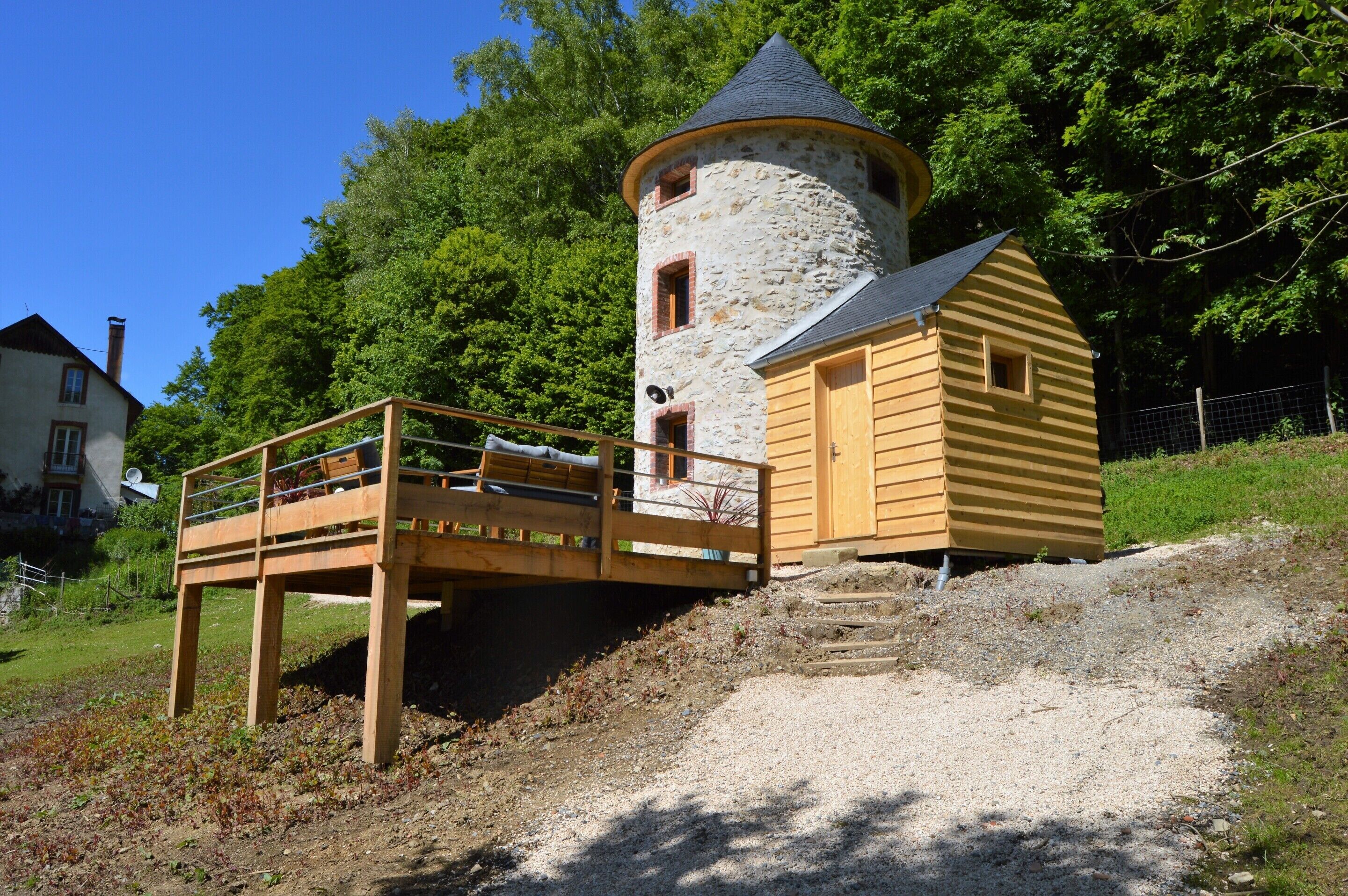 A stone tower with a wooden deck and a yellow building adjacent to it.