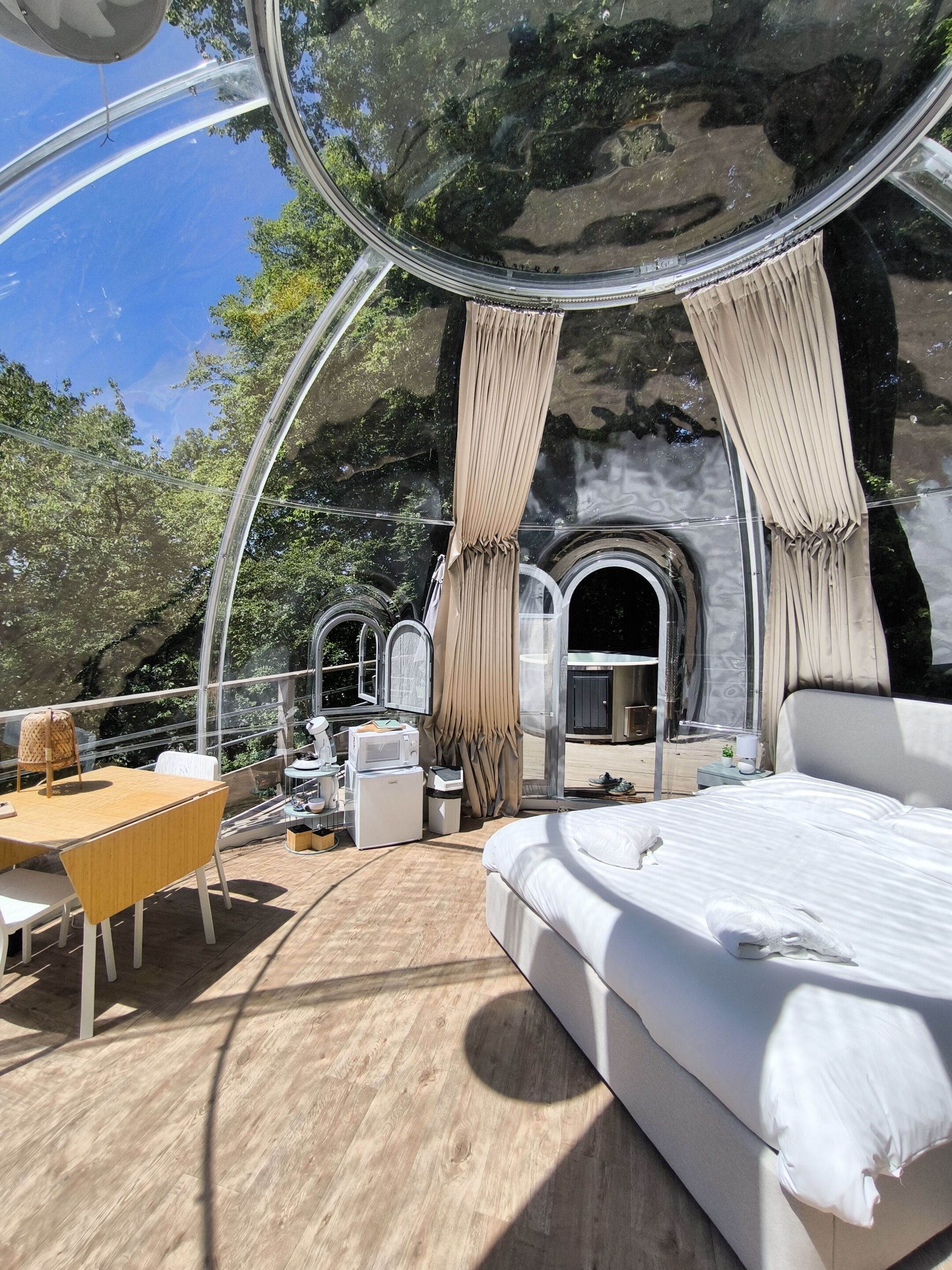 Una habitación moderna y circular con una cama, una mesa y un pequeño rincón de cocina.