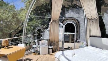 Una habitación moderna y circular con una cama, una mesa y un pequeño rincón de cocina.