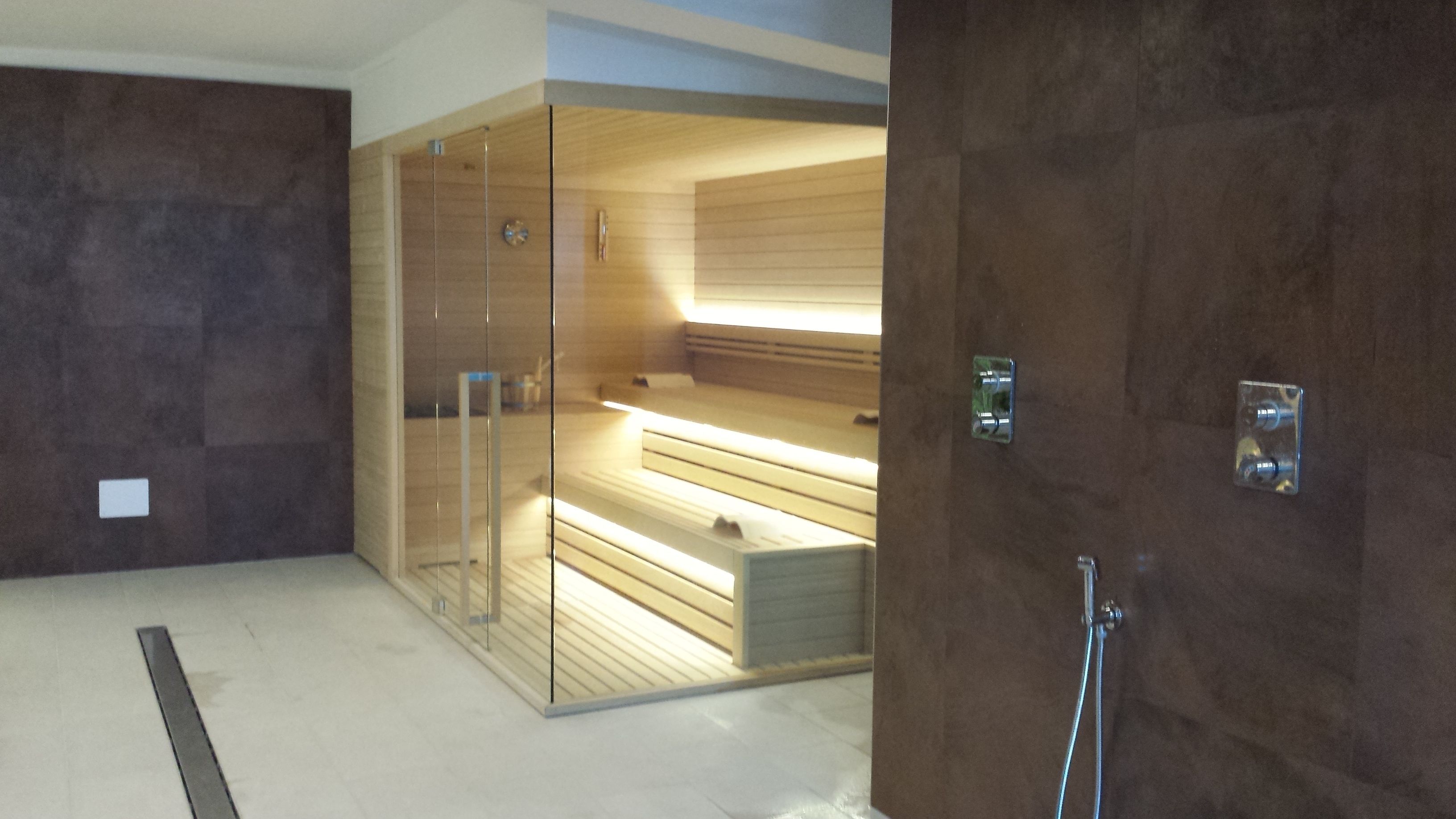 A modern bathroom with a wooden vanity, a glass shower enclosure, and a visible towel rack.