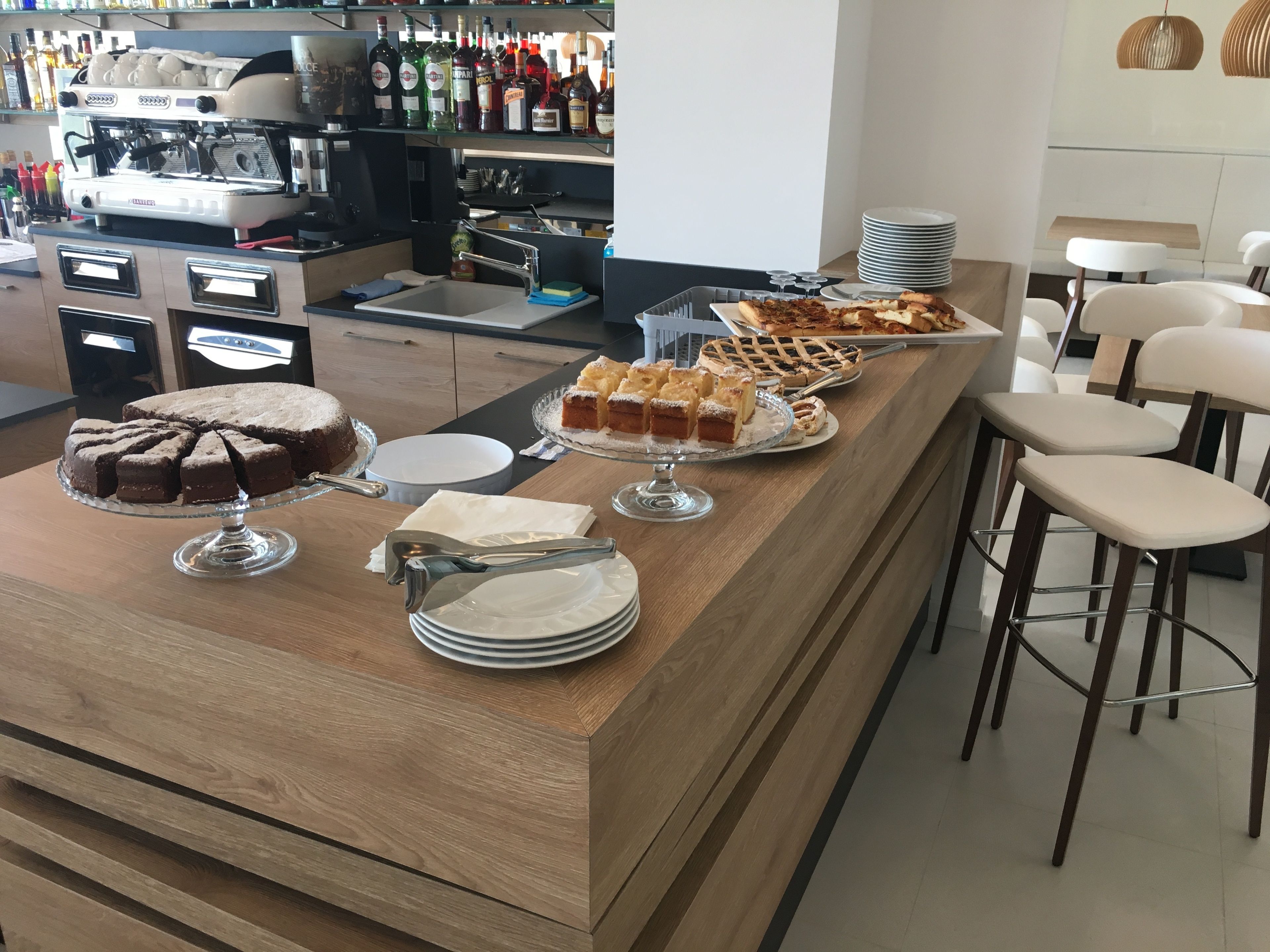 A buffet counter with various desserts, a coffee machine, and bar stools.