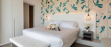 Une chambre à coucher moderne avec un grand lit, des tables de chevet, un banc et une armoire.