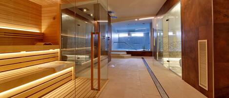 A modern spa area with wooden benches, glass partitions, and a tiled floor.