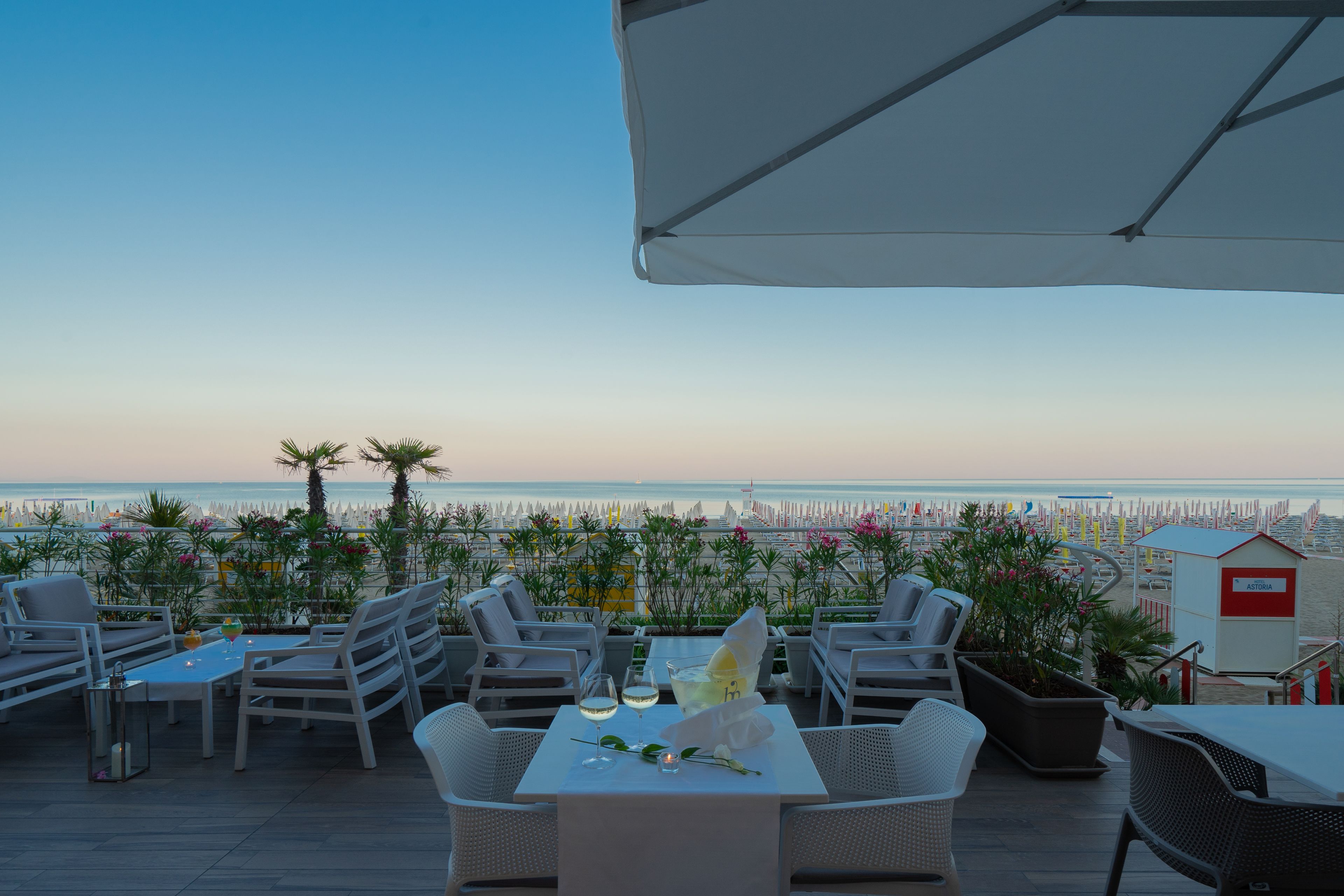 A terrace with a table set for two, overlooking a beach and the sea.
