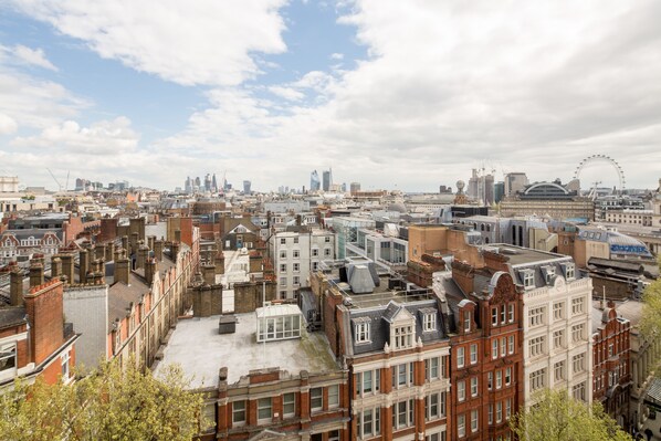 Un paisaje urbano con una mezcla de edificios históricos y modernos, incluyendo una noria destacada en la distancia.