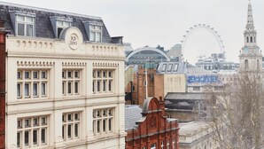 A historic building with a clock tower and a large Ferris wheel in the background.