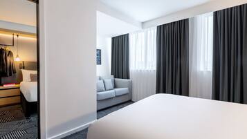 A hotel room with a large bed, a sofa, and a wardrobe.