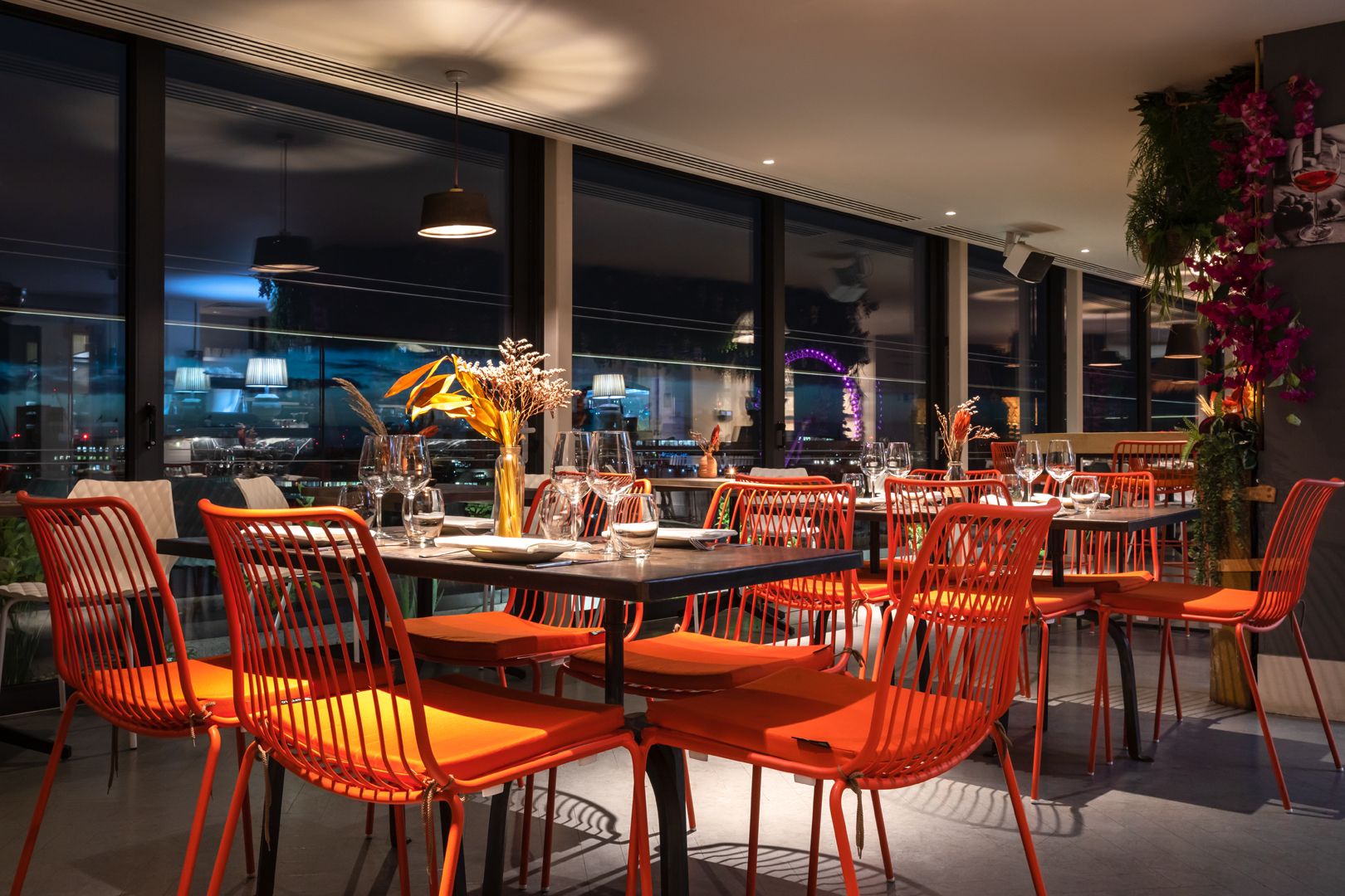 Un espace de restauration moderne avec des chaises et des tables rouges, de grandes fenêtres et une vue sur la ville.