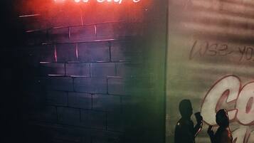 A brick wall with graffiti and a neon sign.