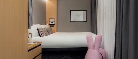 Habitación de hotel con cama, armario de madera, mesita de noche, una silla rosa y una cita enmarcada en la pared.