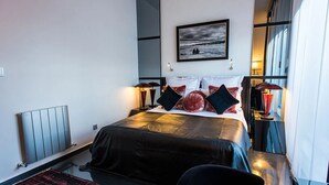 Habitación de hotel moderna con una cama grande, vistas al mar y un sofá de cuero negro.