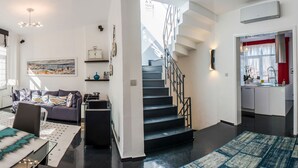 Una sala de estar moderna con una mesa de comedor de vidrio, un sofá y una escalera que sube a un piso superior.