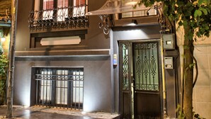Un edificio de dos pisos con entrada a nivel de calle y ventanas en el nivel superior adornadas con barandillas de hierro decorativo.