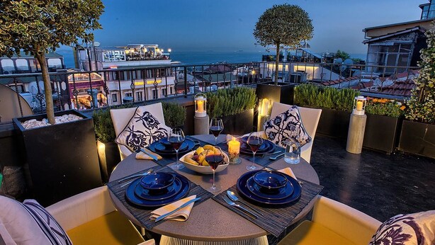 Un espacio para comer en la azotea con una mesa dispuesta para dos, con vistas a la ciudad y al mar.