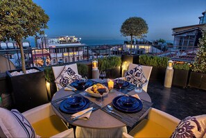 Un espacio para comer en la azotea con una mesa dispuesta para dos, con vistas a la ciudad y al mar.