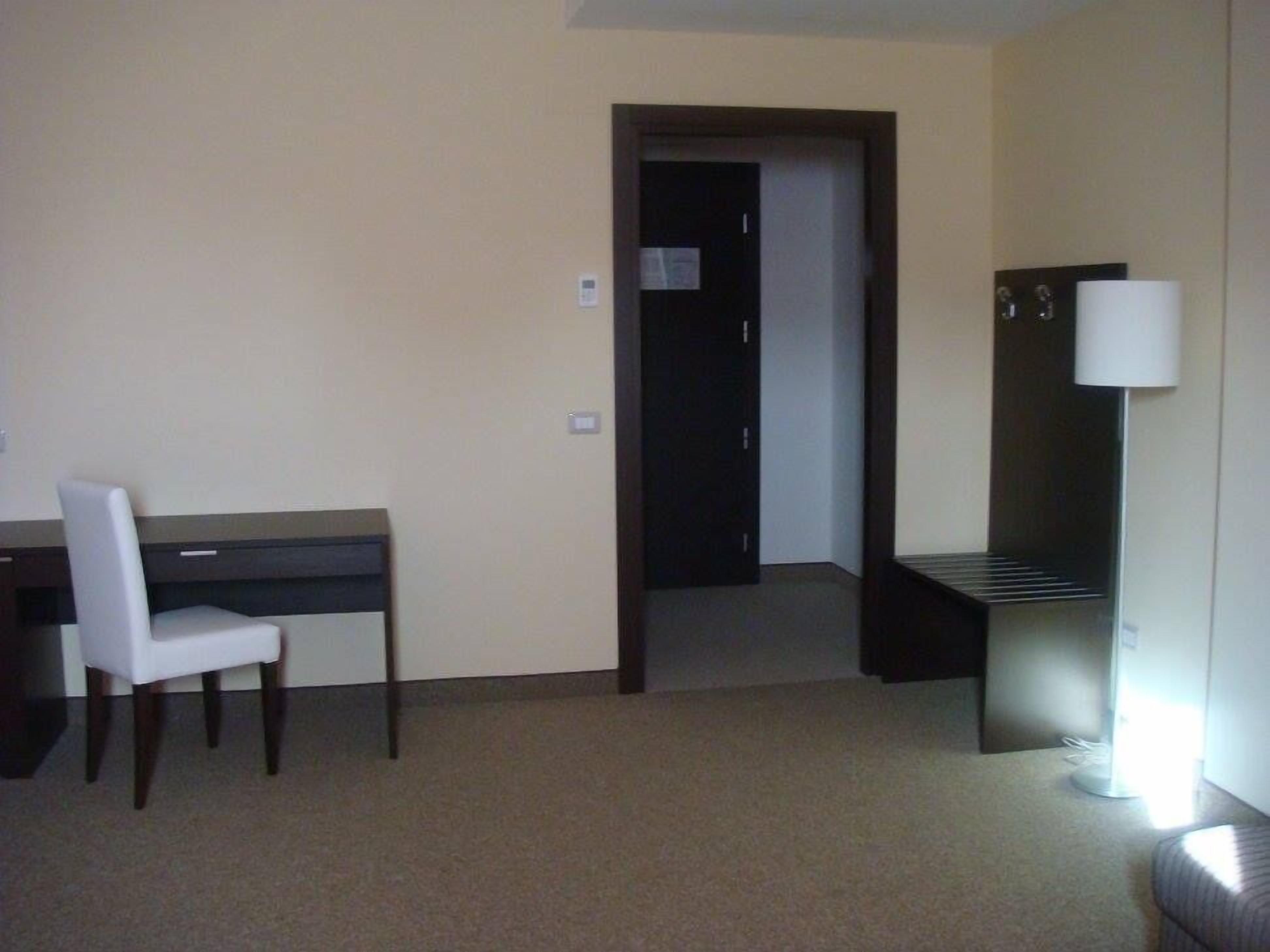 Une chambre d’hôtel équipée d’un bureau, d’une chaise et d’une lampe.