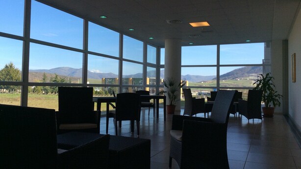 A spacious indoor area with large windows offering a view of mountains and a clear sky. - Hotel Residence Santa Loja (Tito)