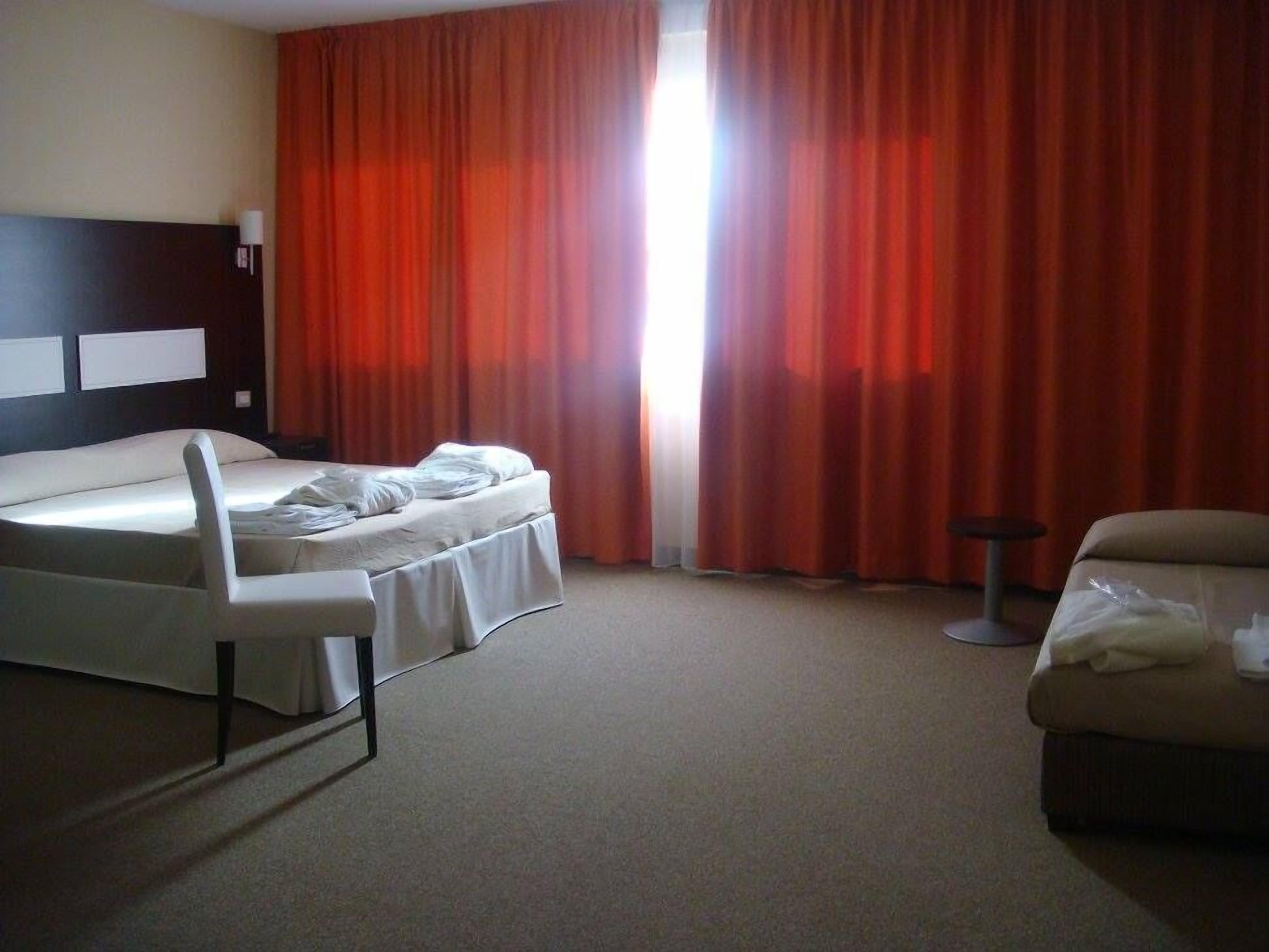 Une chambre d’hôtel avec un lit, une chaise, une petite table et un canapé.