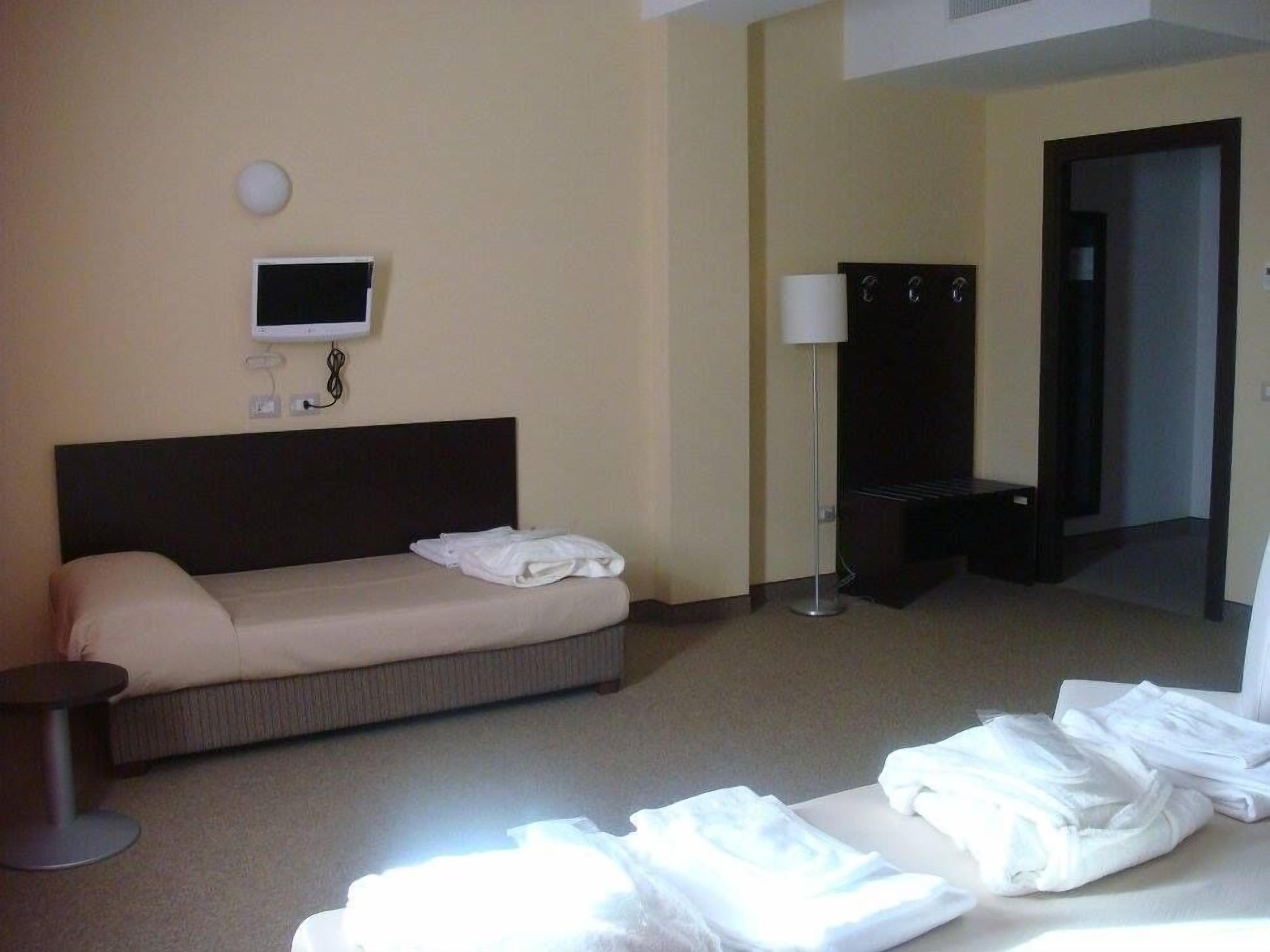 A hotel room with a bed, a TV, a lamp, and a wardrobe.