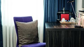 Een kamer met een paarse stoel, een houten bureau en een rood voorwerp op het bureau.