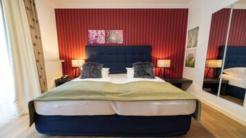 A hotel room with a large bed, two bedside lamps, a mirror, and a red-striped wall.