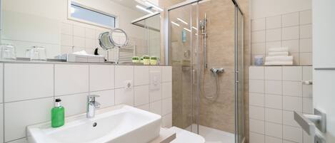 A modern bathroom with a white sink, toilet, and glass-enclosed shower.
