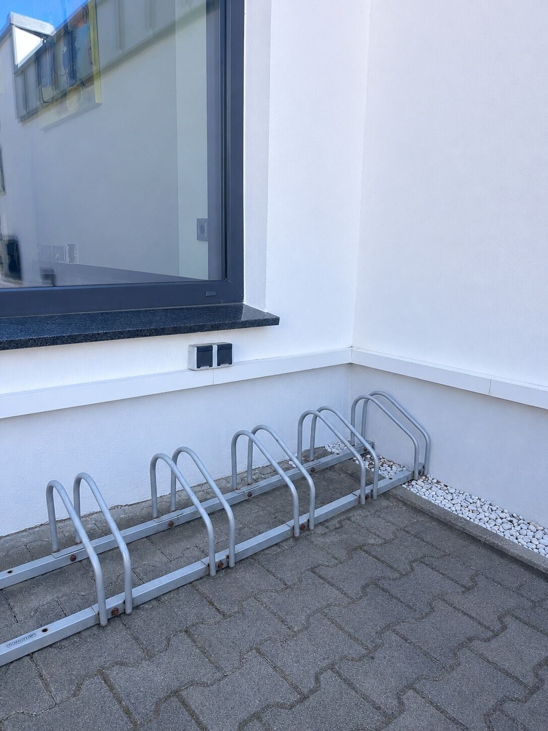 A window with a metal bike rack attached to the wall.