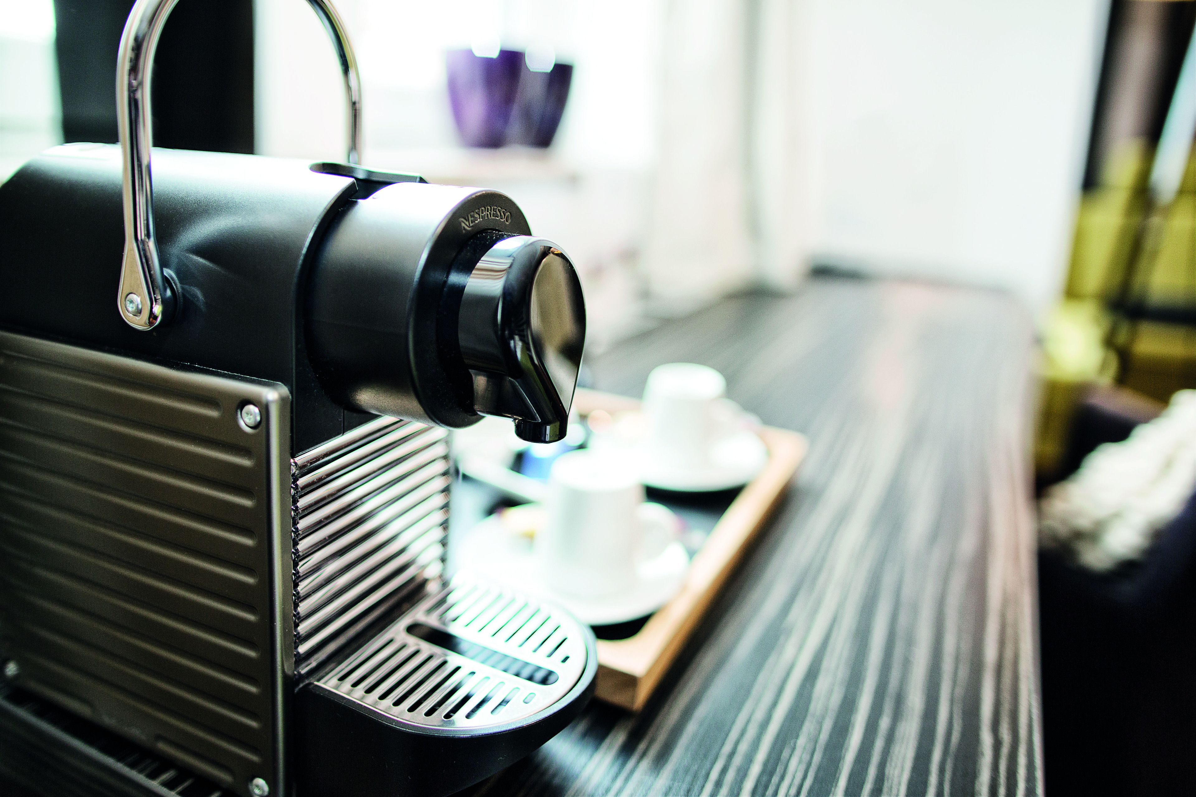 A coffee machine on a tray with a cup and saucer.