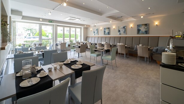 A modern restaurant with a mix of dining and seating areas, featuring a variety of table and chair arrangements. - City Hotel Bosse (Bad Oeynhausen)