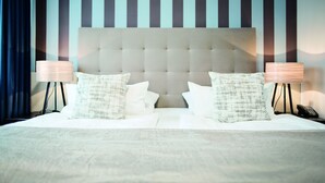 A hotel room with a large bed, two bedside lamps, and striped wallpaper. - City Hotel Bosse (Bad Oeynhausen)