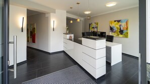 A modern kitchen with a central island, pendant lighting, and a large abstract painting on the wall. - City Hotel Bosse (Bad Oeynhausen)