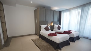 Habitación de hotel moderna con dos camas, un armario grande y vistas al exterior.