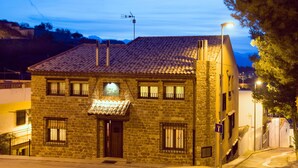 Um edifício de pedra com telhado de telhas, uma placa sobre a entrada e um poste de luz nas proximidades.