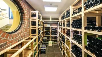 A wine cellar with shelves stocked with wine bottles, a brick wall, and a skylight.