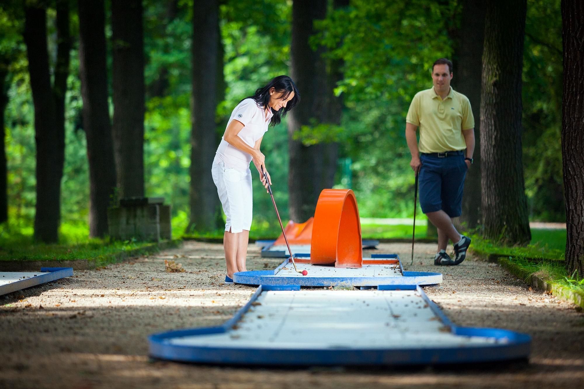 Henkilö pelaa shuffleboardia puukentällä puistossa.