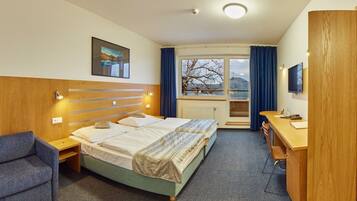 Habitación de hotel con cama, escritorio, silla y televisor.