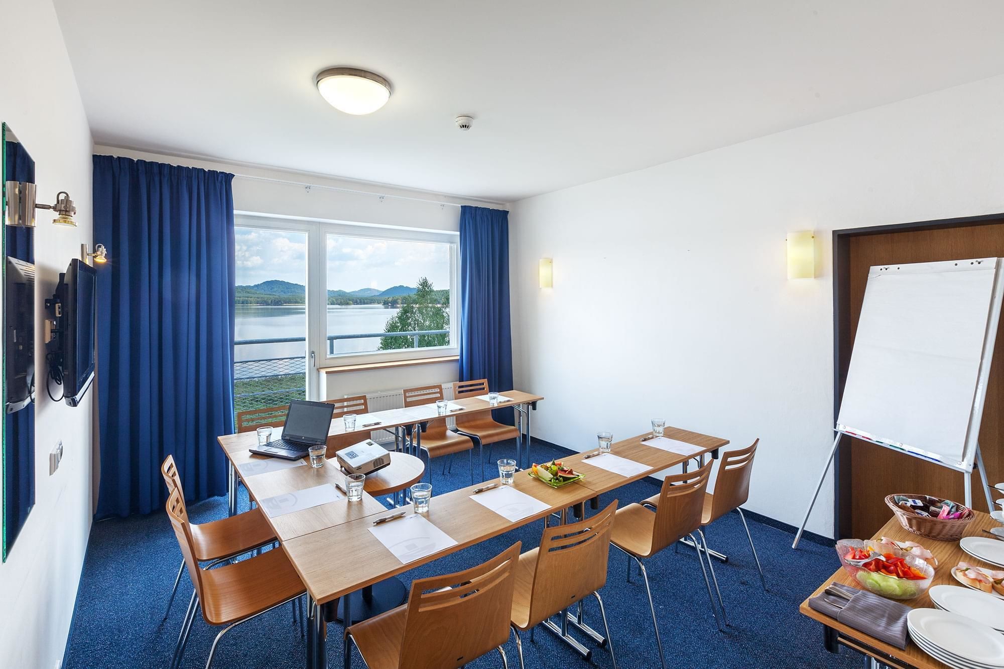 Ein Konferenzraum mit großem Tisch, Stühlen, Projektor und Whiteboard.