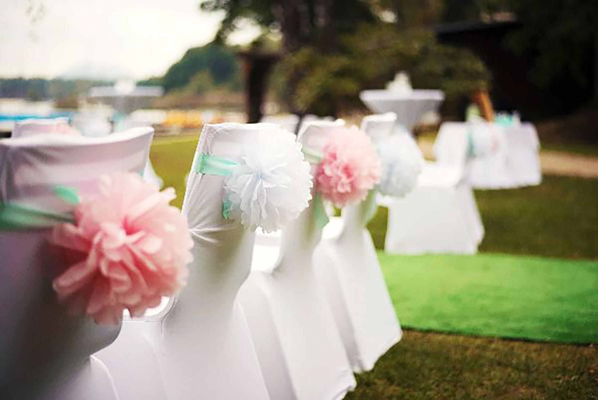 Una fila de mesas blancas con centros de mesa decorados con motivos florales en rosa y blanco.