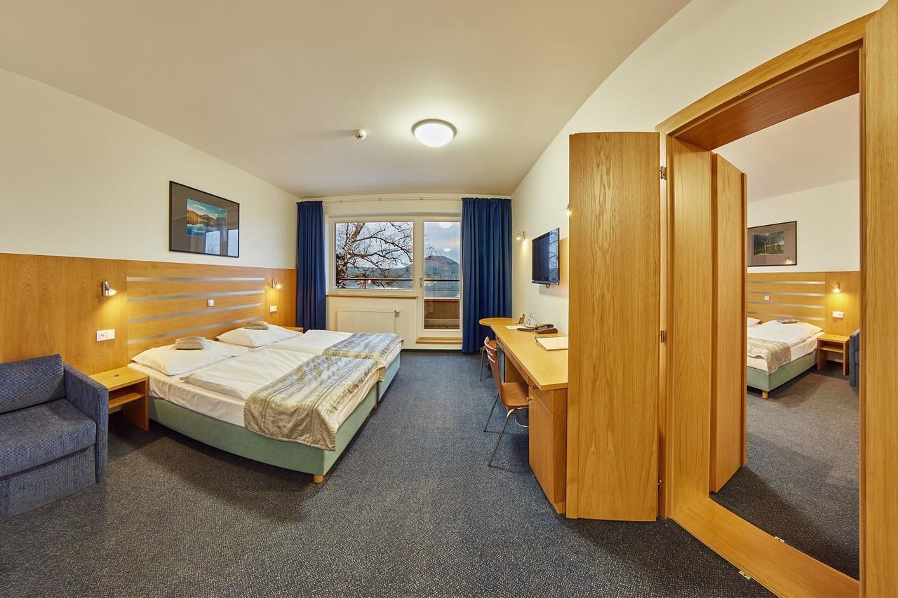 A hotel room with two beds, a desk, a chair, a TV, and a large mirror.
