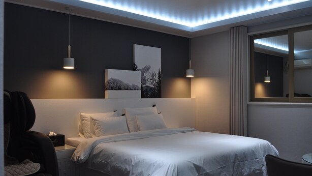 A modern hotel room with a large bed, bedside tables, a small table, and a chair. - Hound Hotel Sangmu (Gwangju)