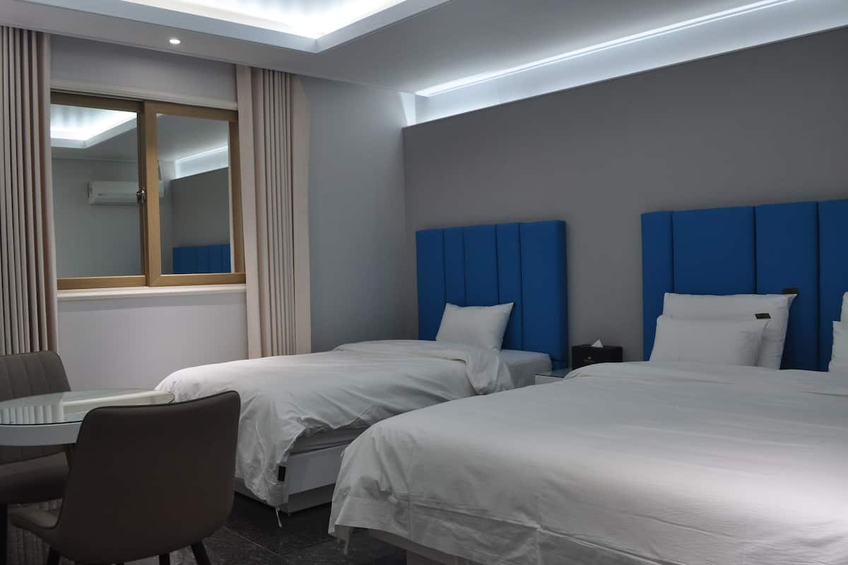 A hotel room with two beds, a desk, and a chair.