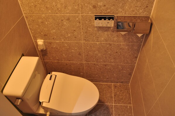 Un baño pequeño con inodoro, secamanos y dispensador de toallas de papel.