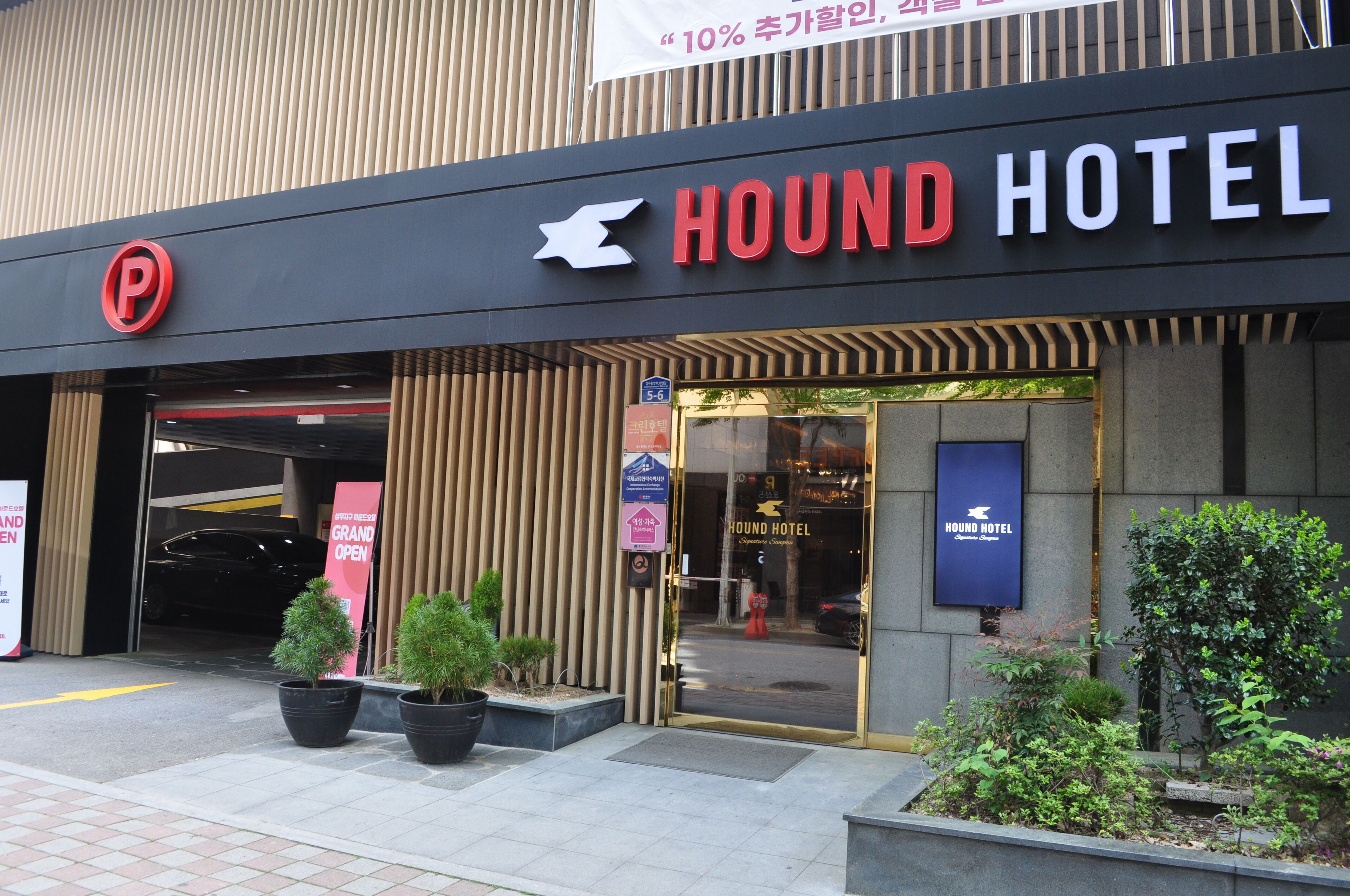 The exterior of the Hound Hotel with a parking sign, entrance, and a sign indicating a 10% discount.