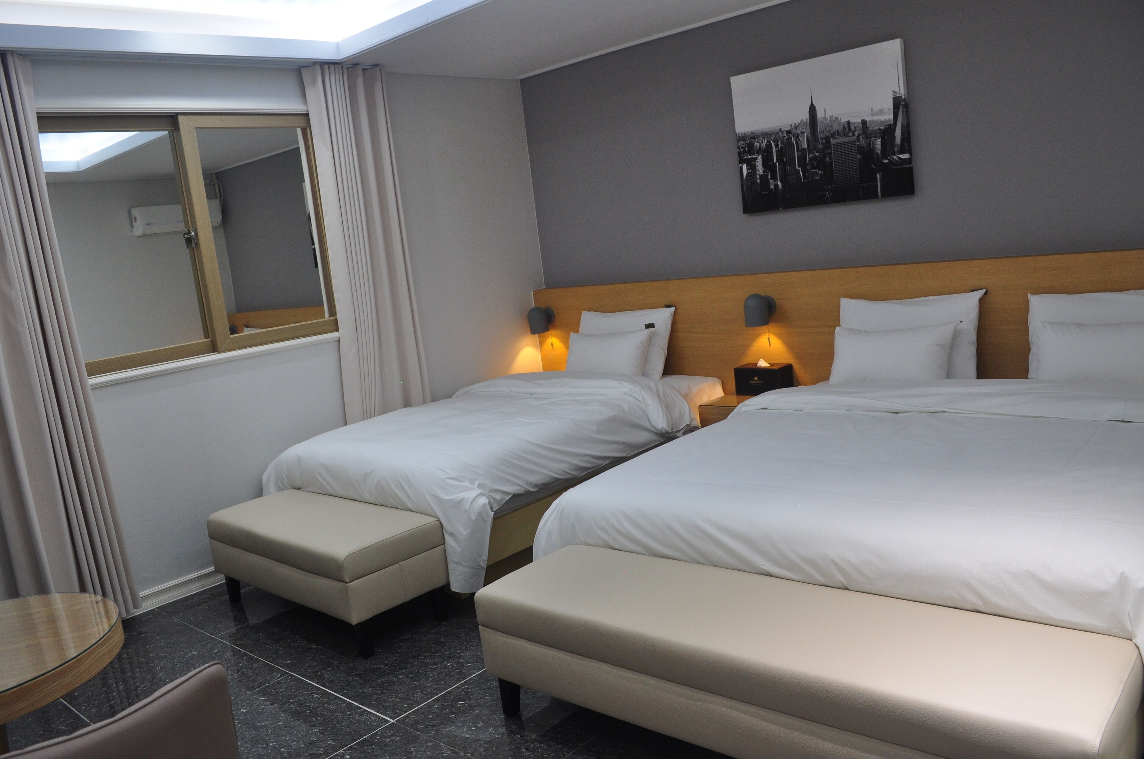 A hotel room with two beds, a small table, and a chair.