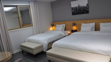 A hotel room with two beds, a small table, and a chair.