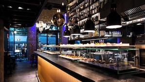 A bar area with a long counter displaying various food items, a wine rack, and hanging pendant lights. - Pytloun Boutique Hotel Prague (Prague)