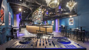 A modern bar with a DJ setup, shelves of bottles, and a bar counter. - Pytloun Boutique Hotel Prague (Prague)
